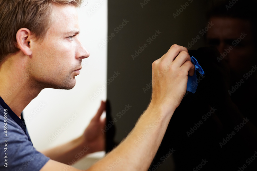 Noticing each speck of dust. Young man cleaning the screen of his smart TV. Noticing each speck of dust. Young man cleaning the screen of his smart TV.