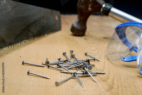 hammer and nails on wood with handsaw and safety glasses