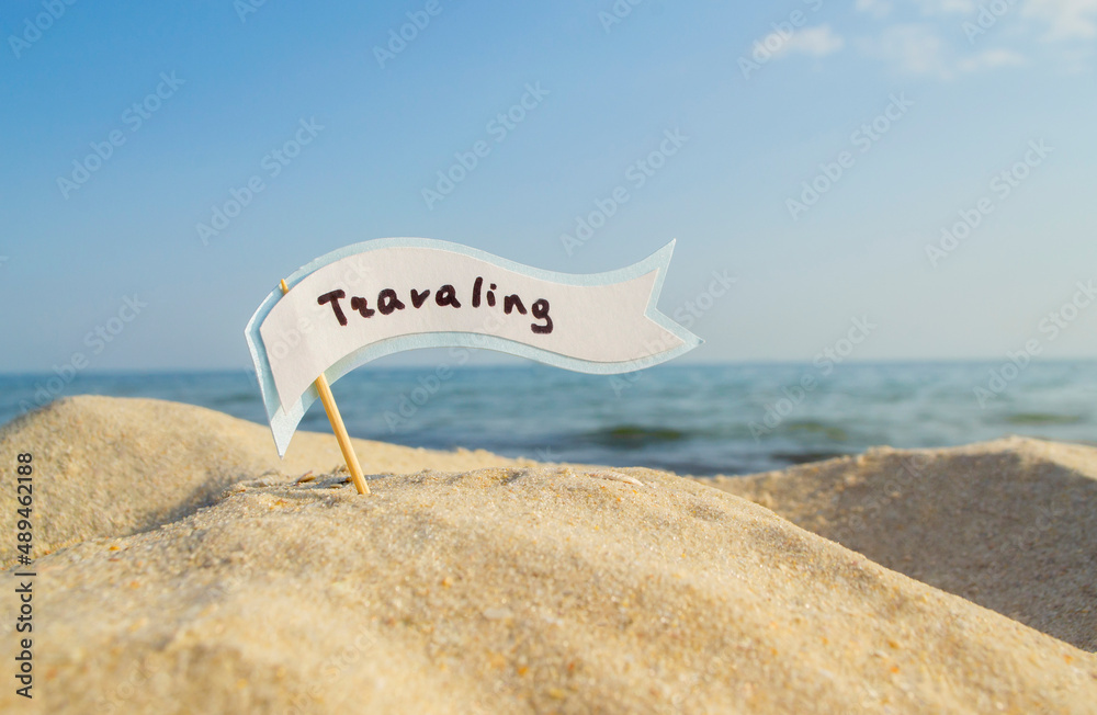 Paper Blue White Blank Speech Bubble on Stick With Word Traveling in Sandy Beach on Background Clean Blue Sky and Sea Close-up on Sunny Summer Day. Concept Travel, Tourism, Vacation, Rest. Copy Space Paper Blue White Blank Speech Bubble on Stick With Word Traveling in Sandy Beach on Background Clean Blue Sky and Sea Close-up on Sunny Summer Day. Concept Travel, Tourism, Vacation, Rest. Copy Space