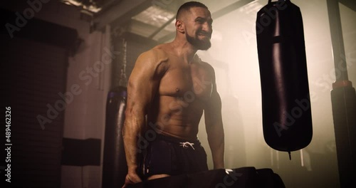 A Mid Shot Of A Hispanic Bodybuilder Tyre Walking In A Crossfit Gym. Shot In A Crossfit Boxing Gym With Low Key Lighting And A Scattering Of Haze. Captured On Red Digital Cinema Camera 