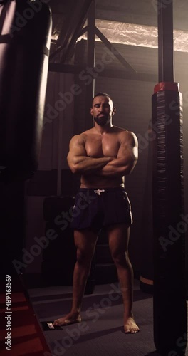 A Vertical Video Portrait Of A Hispanic Bodybuilder In An MMA Gym. Shot In A Crossfit Boxing Gym With Low Key Lighting And A Scattering Of Haze. Captured On Red Digital Cinema Camera 