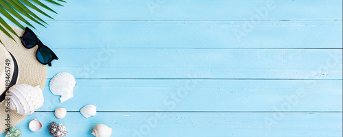 Summer beach background / high angle of the hat slippers And sunglasses on the blue wooden floor of palm trees