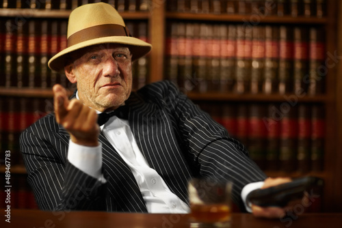 He heads up a large criminal organisation. Aged mob boss wearing a hat and looking serious while pointing. photo
