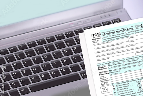 File taxes online with a computer laptop or with the IRS paper 1040 Tax Return form