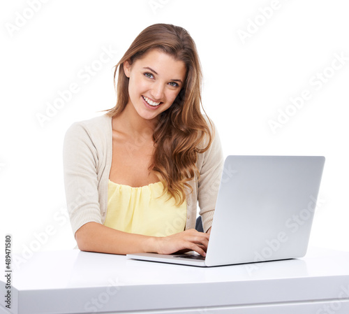 Making the most of technology. Studio shot of an attractive young woman sitting at a table and using a laptop.