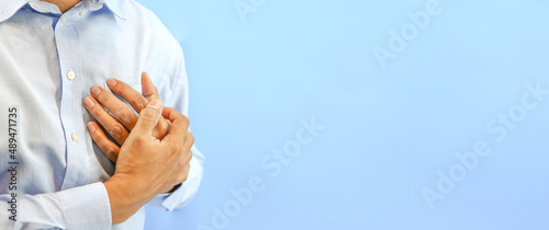 Photos Hand squeezing the left chest pain on blue background concept of heart attack and warning illness heartache angina or heart disease