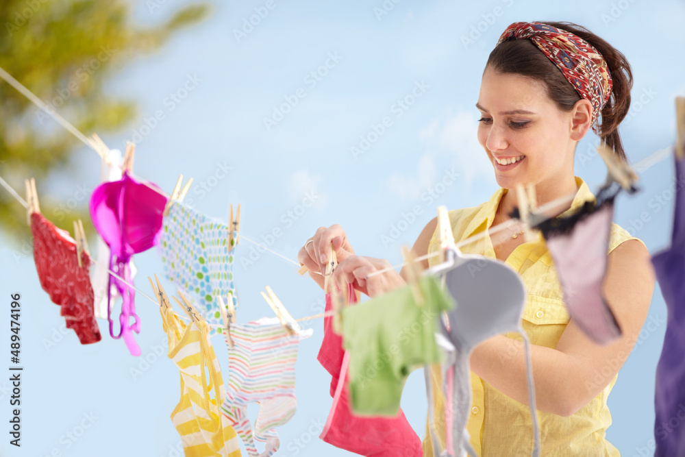 Fototapeta premium Its laundry day. Attractive young woman hanging up her washing on a line outside.