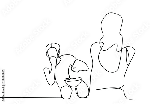 A man watching television with excitement and a woman walking in front of his television.