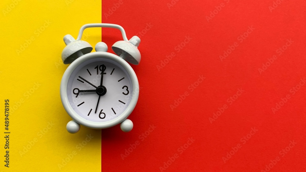 White alarm clock on with yellow and red background. Conceptual White alarm clock on with yellow and red background. Conceptual