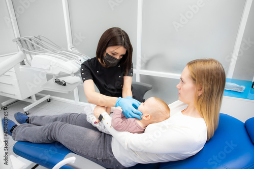 mom and baby at the reception at the pediatric dentist. First visit to the dentist. Diagnosis and treatment of milk teeth in children and infants photo