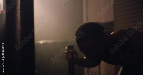 An African American and Hispanic Athlete Sled Push Training In A Gym. Shot In An MMA Boxing Gym With Low Key Lighting And A Scattering Of Haze. Captured On Red Digital Cinema Camera 