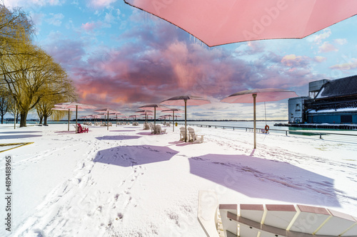 ugar Beach park down town Toronto with Pink Umbrellas Blue cloudy skies and snow on the ground and beach chairs photo