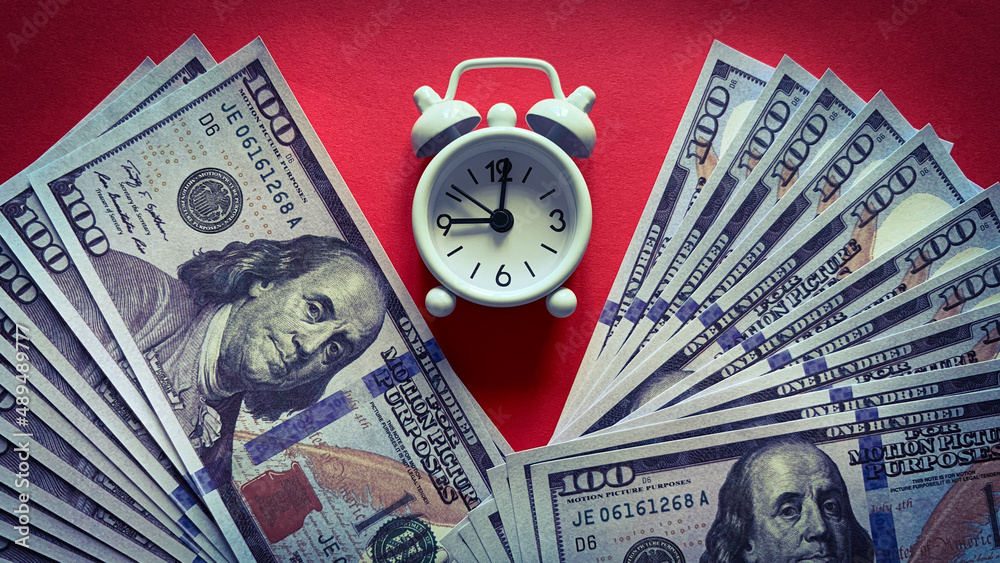 Top view of white alarm clock and bank notes on red background. Copy space concept Top view of white alarm clock and bank notes on red background. Copy space concept