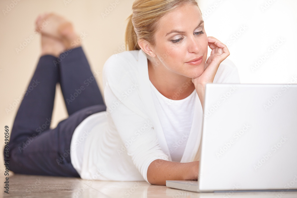Catching up on the daily happenings of her friends. A gorgeous young woman lying on the floor while working on her laptop. Catching up on the daily happenings of her friends. A gorgeous young woman lying on the floor while working on her laptop.