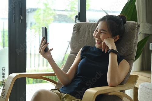 Wallpaper Mural Overjoyed woman resting in comfortable armchair and making video call on smart phone. Torontodigital.ca