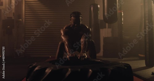 An African American Athlete Exercises, Tyre Pull In A Crossfit Gym. Shot In An MMA Boxing Gym With Low Key Lighting And A Scattering Of Haze. Captured On Red Digital Cinema Camera 