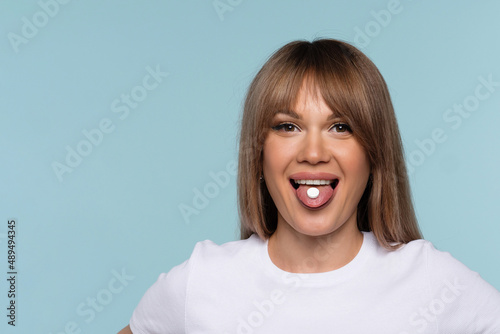 Obraz na plátně Young woman taking pills on blue background