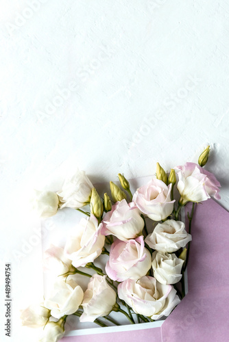 Flower bud flat lay in an envelope lisianthus or eustoma  texas bell and prairie gentian  irish rose  on white background with copy space. Concept for greeting card  mail and congratulations.