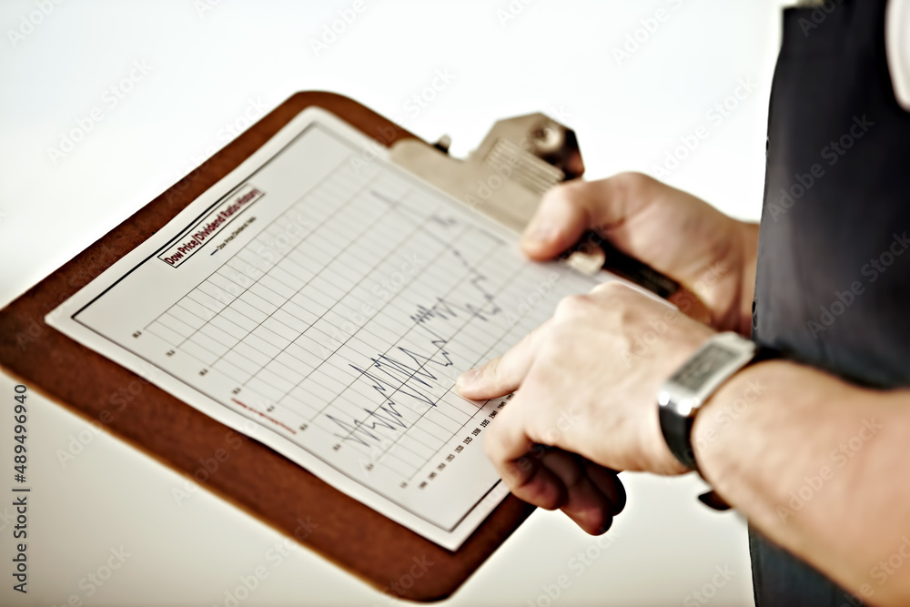 Fototapeta premium Long-term market tracking. A person pointing at a graph on a clipboard.
