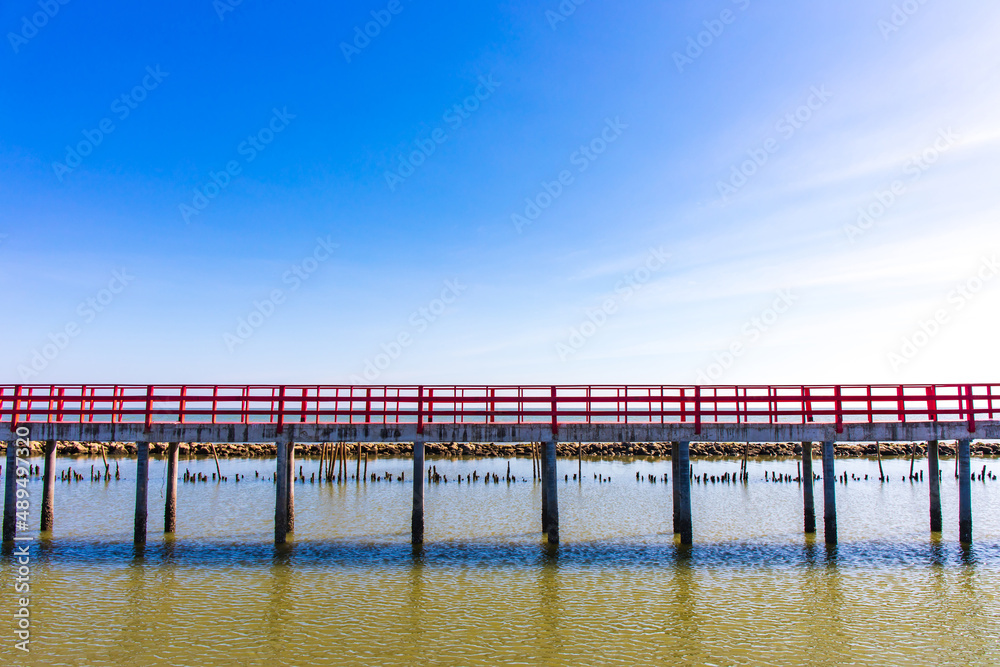 Beautiful landscape photo of red long wooden bridge with blue sky in Samut Sakhon province, Thailand. Asia.