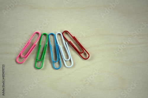 on a wooden surface should be paper clips of red blue green pink white colors