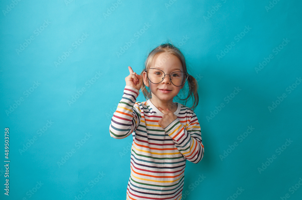 a little girl in big glasses stands on a blue background a little girl in big glasses stands on a blue background