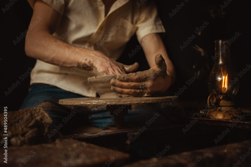 man in pottery workshop makes plate of clay, an authentic atmosphere, yellow lamp, lifestyle, magical atmosphere. Concept with your own hands, home entertainment. low key man in pottery workshop makes plate of clay, an authentic atmosphere, yellow lamp, lifestyle, magical atmosphere. Concept with your own hands, home entertainment. low key