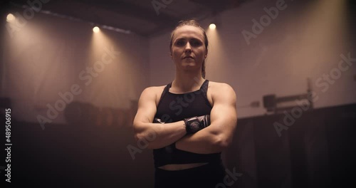 A Portrait Of A Strong Kickboxing Woman In An MMA Gym. Shot In A Crossfit Boxing Gym With Low Key Lighting And A Scattering Of Haze. Captured On Red Digital Cinema Camera 