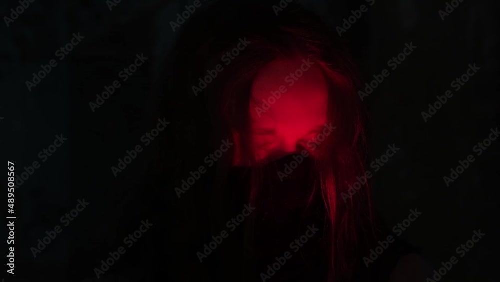 young man with long hair wearing black mask on his face in the light of red candle opening his eyes, slow motion video young man with long hair wearing black mask on his face in the light of red candle opening his eyes, slow motion video