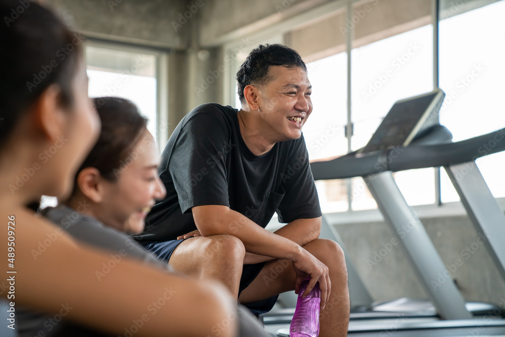 Healthy Asian athletic man and woman in sportswear relaxing cool down after do workout exercise at fitness gym. Male and female do sport training together at sport club. Health care motivation concept Healthy Asian athletic man and woman in sportswear relaxing cool down after do workout exercise at fitness gym. Male and female do sport training together at sport club. Health care motivation concept