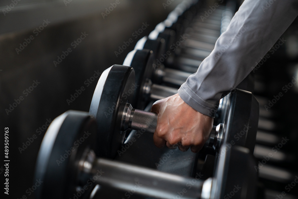 Healthy Asian athlete woman in sportswear workout exercise weight lifting dumbbell at fitness gym. Strong female do body building muscle weight training at sport club. Health care motivation concept Healthy Asian athlete woman in sportswear workout exercise weight lifting dumbbell at fitness gym. Strong female do body building muscle weight training at sport club. Health care motivation concept