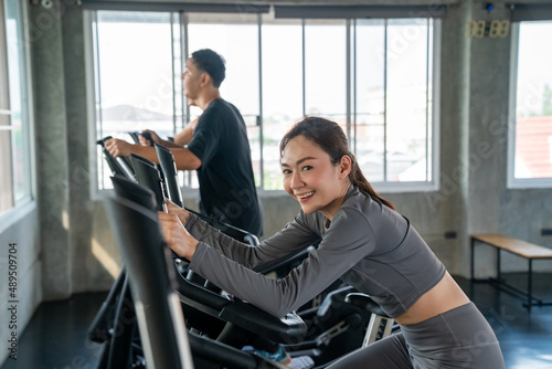 Portrait of Healthy Asian athletic woman in sportswear workout exercise on cycling machine at fitness gym. Wellness female do cardio sport training at sport club. Health care motivation concept