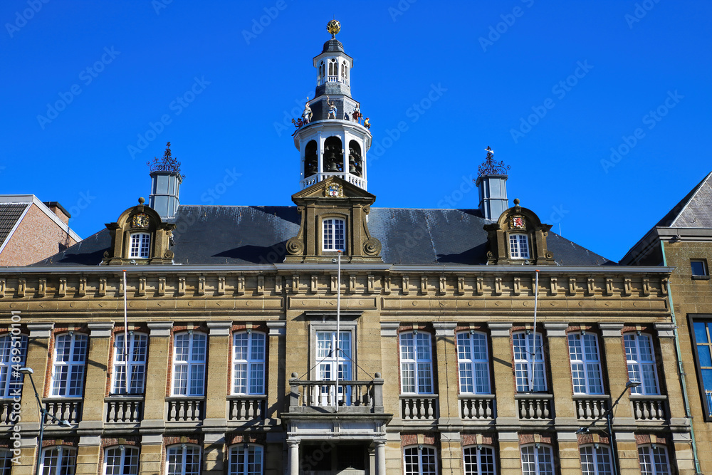 Roermond, Netherlands - February 9. 2022: View on facade of historical town hall with chime tower against blue sky