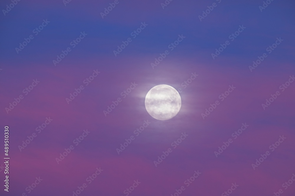 Full Moon Behind Clouds in a Purple Sunrise Sky
