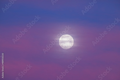 Full Moon Behind Clouds in a Purple Sunrise Sky