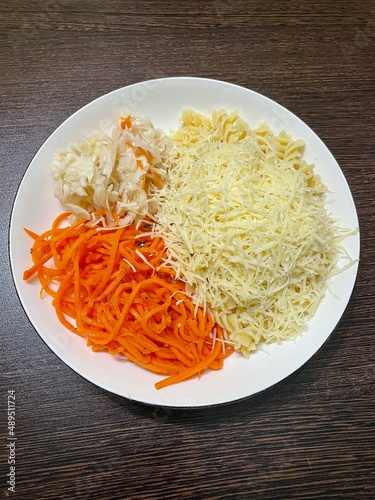 large vertical photo. homemade food. useful healthy foods. round white plate with macaroni and cheese and Korean carrots and sauerkraut. view from above.