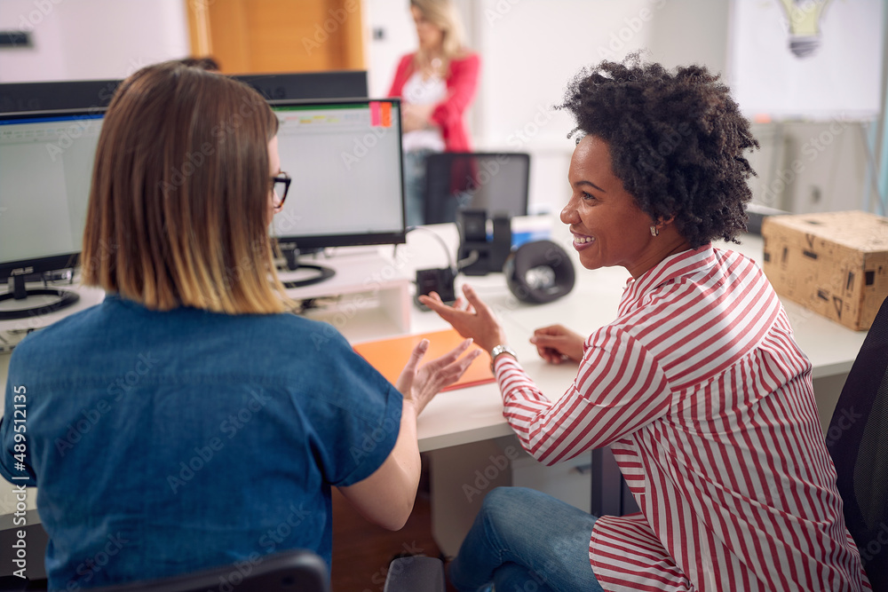 Female colleagues are chatting while working in the office. Employees, job, office Female colleagues are chatting while working in the office. Employees, job, office