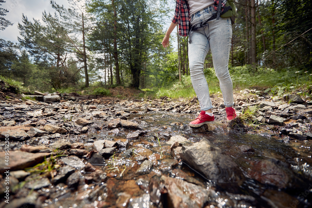 A young girl is crossing a creek while hiking. Hiking, nature, relationship, together A young girl is crossing a creek while hiking. Hiking, nature, relationship, together