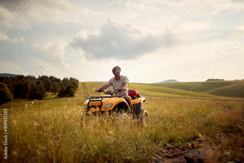 A young man is riding a quad in the nature. Riding, nature, activity