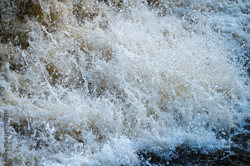 close up of flowing water, rapid water splashes of an white water river or stream, bubbly water