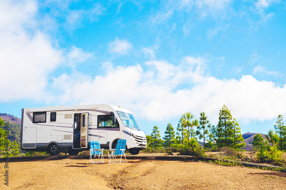 Beautiful tourism camper van campsite in the nature. Travel and rv renting vehicle vacation. Vanlife and wanderlust concept with modern motorhome parked in the nature with blue sky background