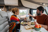 Adult couple enjoy time eating inside camper van in mountain holiday free vacation together. Man and woman in vanlife or tourist activity inside rv motorhome. Travel alternative home concept