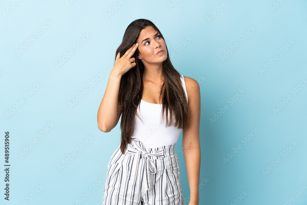Young brazilian woman isolated on blue background with problems making suicide gesture Young brazilian woman isolated on blue background with problems making suicide gesture