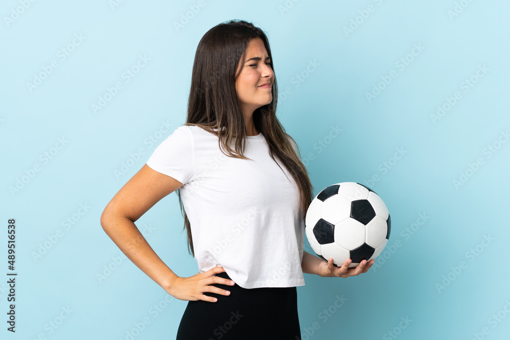 Young football player brazilian girl isolated on blue background suffering from backache for having made an effort