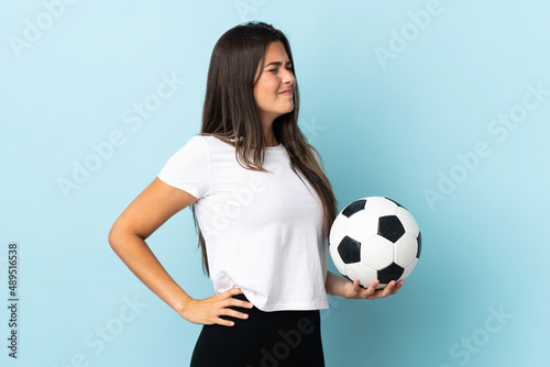 Young football player brazilian girl isolated on blue background suffering from backache for having made an effort