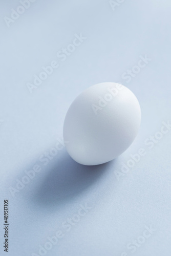 White egg on a blue background. Raw chicken egg close up. Minimal Easter concept