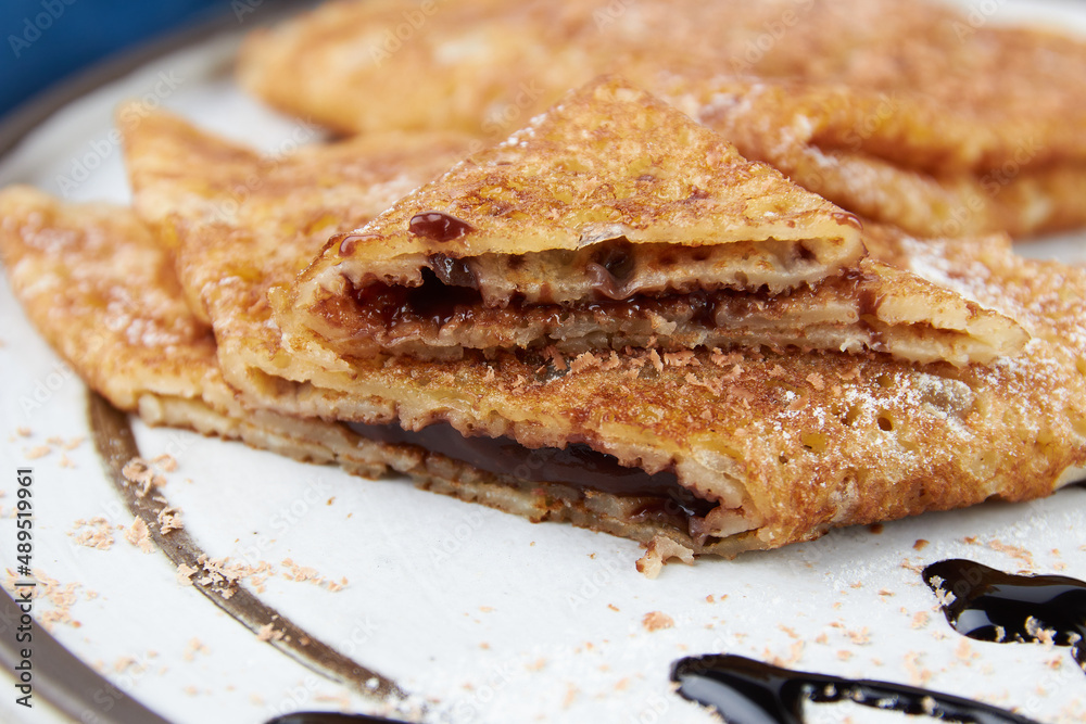 Crepes stuffed on plate, thin pancakes, blini, white wooden table