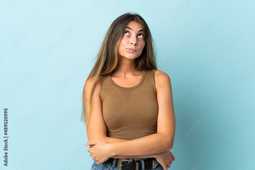 Young caucasian woman isolated on blue background and looking up Young caucasian woman isolated on blue background and looking up