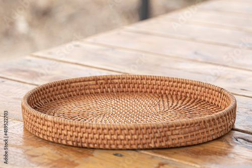 round rattan basket isolated on wooden background. photo