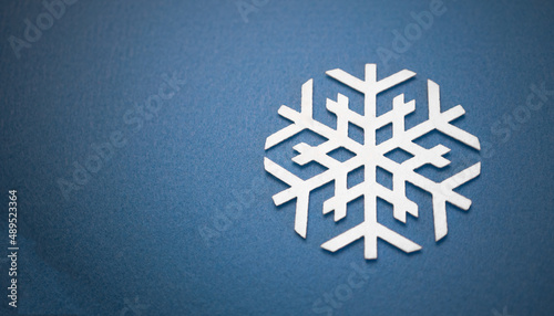 Round snowflake made of white fabric on a blue background. New Year's background.